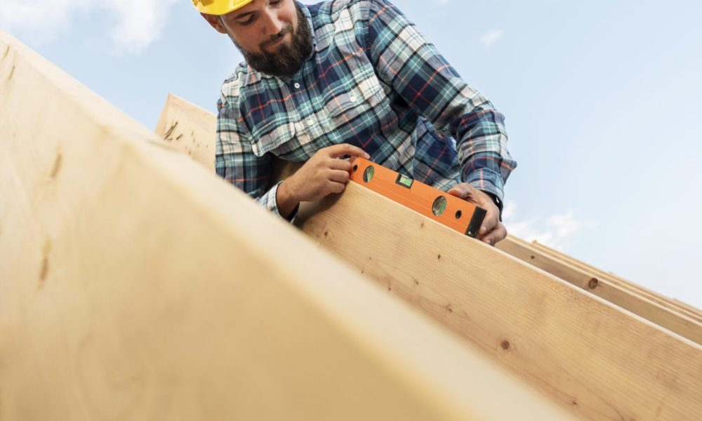 Framing carpenter with level tool on rooftop